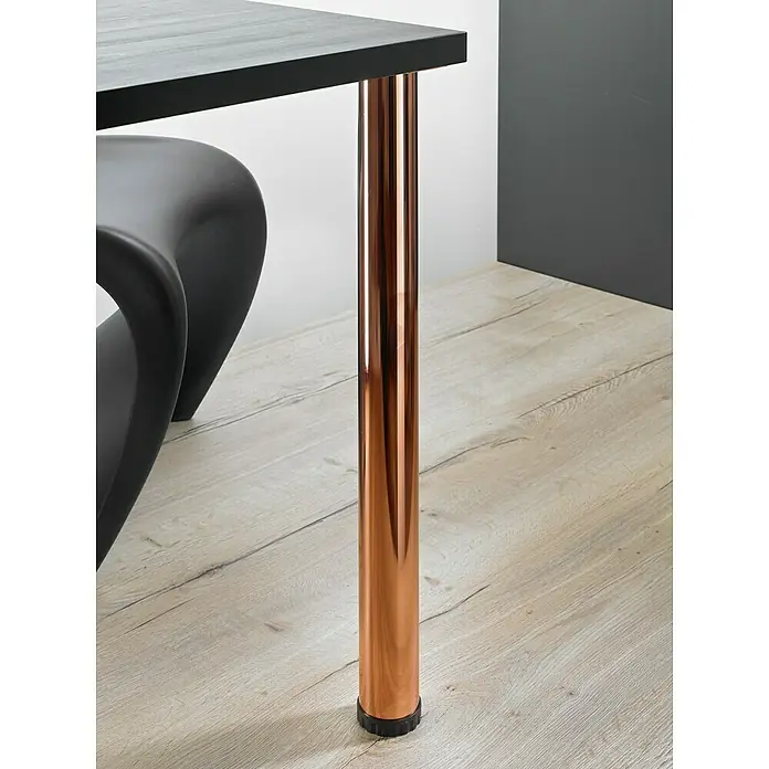 Hettich Möbelfuß Zela - Ø x H: 6 x 70 cm, Traglast: 100 kg, Stahl, Kupfer - Naheaufnahme eines Tisches mit kupferfarbenen Beinen, einer schwarzen Tischplatte und einem modernen Stuhl auf einem hellen Holzboden.
