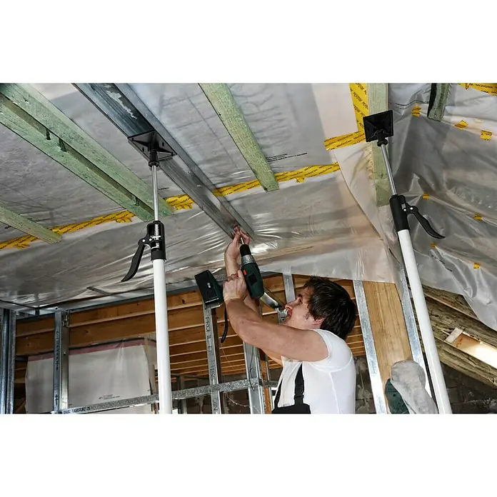 Schnellspann Deckenstützen & Türspanner Montagestütze - Spreizweite: 121 cm - 290 cm - Der Heimwerker befestigt mit einer Stütze ein Metallprofil an einer Decke, während er es mit einer Bohrmaschine festschraubt.
