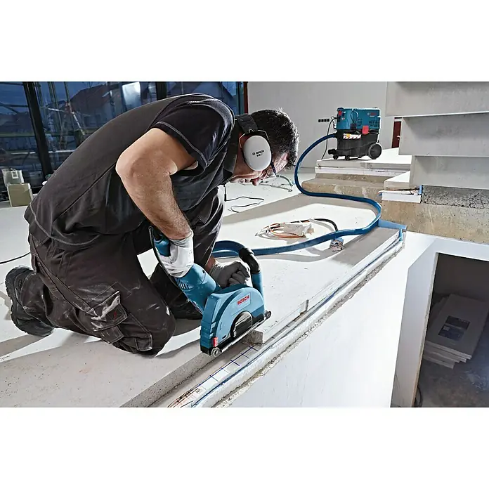 Bosch Professional Absaugvorrichtung - Passend für: Bosch Winkelschleifer GWS-Serie mit Ø 230 mm - Handwerker schneidet mit einer Bosch Mauernutfräse einen Schlitz in eine Betonwand. Staub wird direkt abgesaugt.