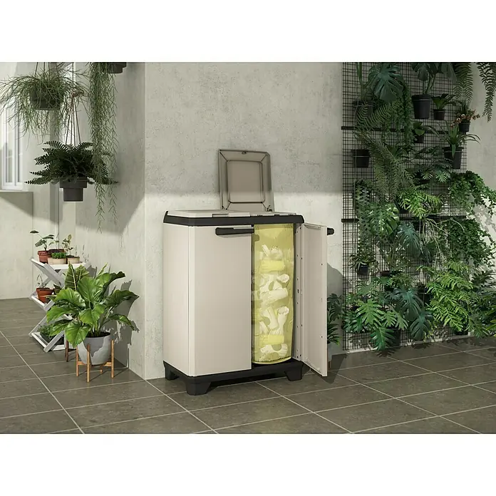 Keter Kunststoff-Mehrzweckschrank Planet für Müllbeutel - L x B x H: 39 x 68 x 90 cm - Hier ist ein beiger Gartenschrank mit geöffneter Tür, der gelbe Müllsäcke zeigt, vor einem Hintergrund mit verschiedenen Pflanzen.