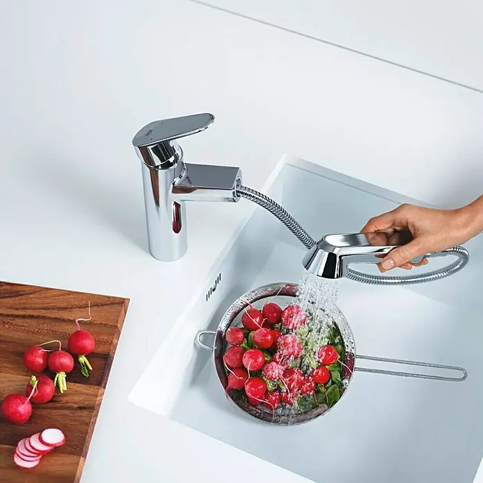 Grohe Eurodisc Cosmopolitan Spültischarmatur - Chrom, Glänzend, Anzahl Strahlarten: 2 Stk. - Eine moderne Küchenarmatur von Grohe wird verwendet, um frische Radieschen in einem Sieb zu waschen.