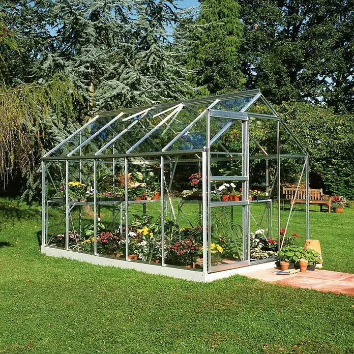 Halls Gewächshaus Popular 106 - Außenmaß inkl. Dachüberstand (B x T): 193 x 319 cm, Material Seitenwand: Glas, 3 mm, Silbergrau - Gewächshaus mit Glasplatten und Metallrahmen, gefüllt mit bunten Blumen und Pflanzen, im Garten aufgestellt.