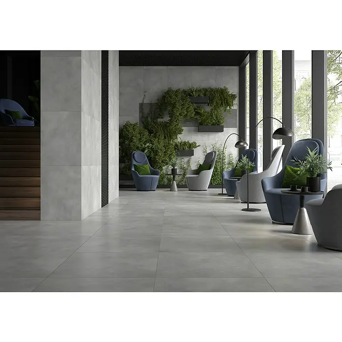 Feinsteinzeugfliese Dimension - 79,7 x 79,7 cm, Grafit, Matt - Elegantes Interieur mit großformatigen Bodenfliesen in Grau, ergänzt durch bequeme Sessel und üppige Pflanzenwände für eine moderne Atmosphäre.