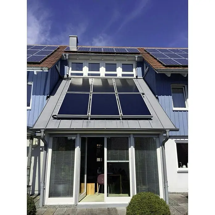 Sunset Solaranlage Sunsol 8 HZ/2 - Mit Frischwasserspeicher 825 l, Kollektorfläche: 15,06 m², Geeignet für: 3 - 6 Personen (Einfamilien- oder Mehrfamilienhaus) - Das Bild zeigt ein Haus mit Solarpaneelen auf dem Dach und einer Glasveranda mit Jalousien. Die Paneele erzeugen umweltfreundliche Energie.