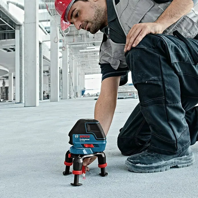 Bosch Professional Láser de línea GLL 3-50 - Zona de trabajo: 50 m (con receptor), 5 pzs. - Un trabajador de la construcción usa un láser de líneas Bosch GLL 3-50 Professional con trípode en una obra para mediciones precisas.