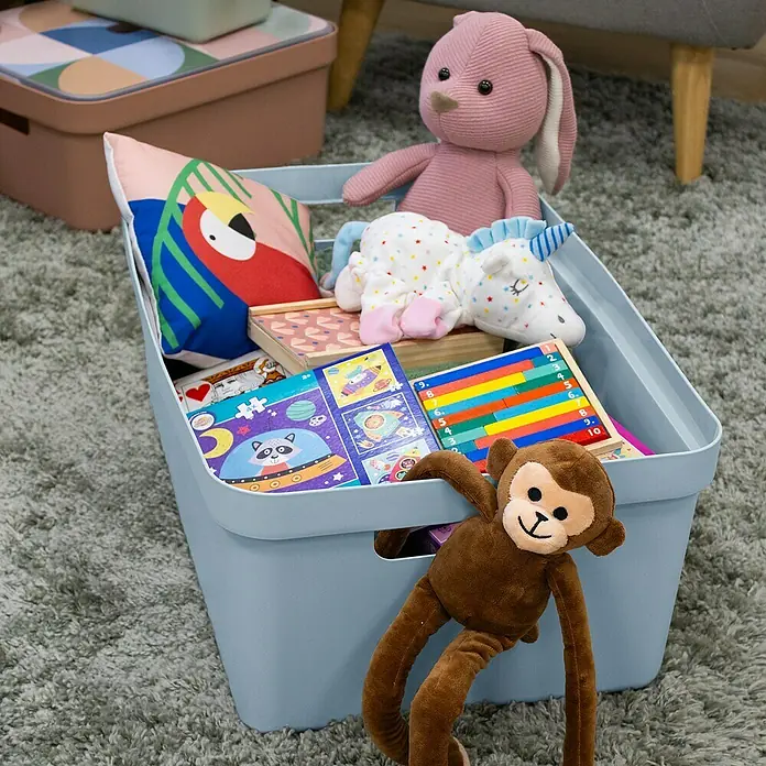 Sunware Aufbewahrungsbox Sigma Home - L x B x H: 59 x 39 x 24,2 cm, Kunststoff, Blaugrau - Hellblaue Aufbewahrungsbox für Spielzeug mit Plüschtieren, Kissen und bunten Spielsachen auf einem Teppich.