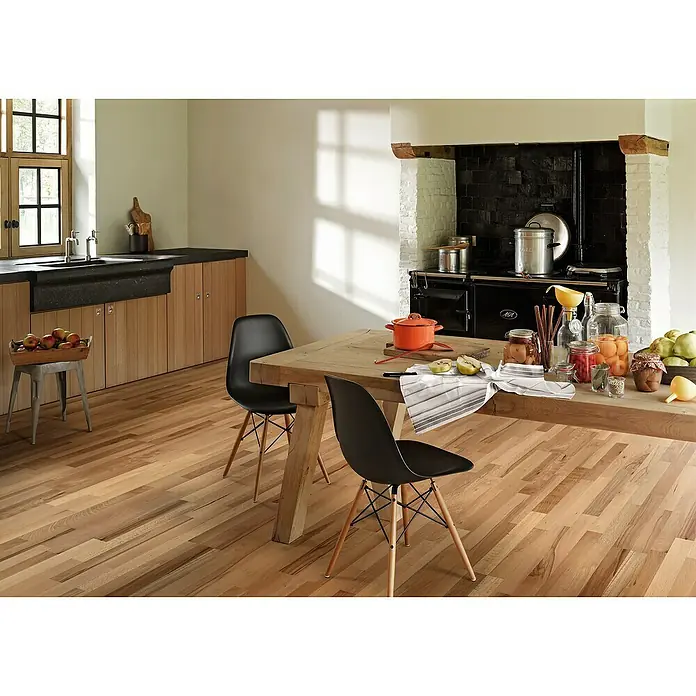 Parador Parkettmuster Classic 3060 Living Buche - 200 x 185 x 13 mm, Schiffsboden - Küche mit Holzboden, Esstisch mit Speisen und schwarzen Stühlen. Der helle Holzboden erzeugt eine einladende Atmosphäre im Raum.