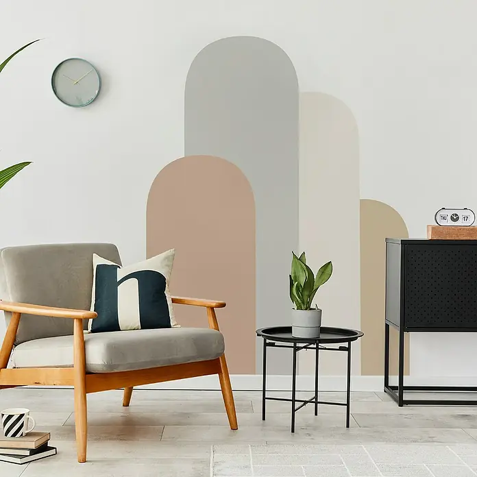 Vinilo de pared autoadhesivo Arco Zenda - 132 x 170 cm, Multicolor, Plástico - Elegante interior de sala de estar con sillón gris, mesa auxiliar negra con planta y decoración de pared abstracta.
