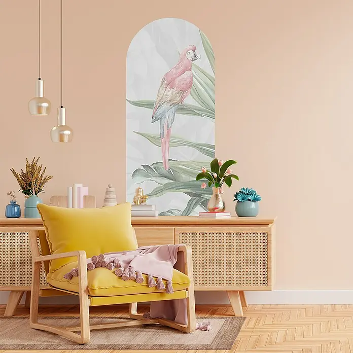 Vinilo de pared autoadhesivo Arco Lilo - 65 x 200 cm, Multicolor, Plástico - Salón con sillón amarillo, aparador decorado y un mural con un loro rosa, creando un ambiente tropical.