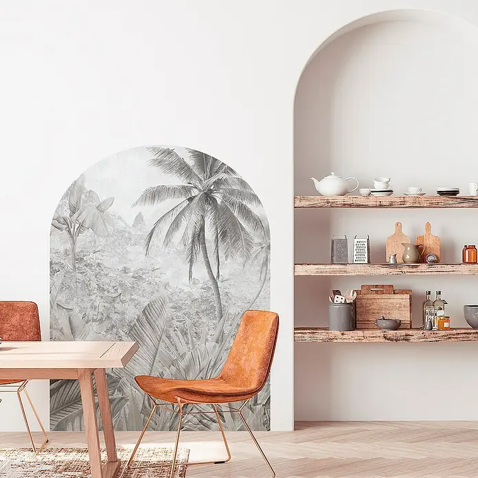 Vinilo de pared autoadhesivo Arco Tropic Dune - 132 x 170 cm, Blanco/Negro, Plástico - Interior con mural tropical, mesa de madera y estanterías con vajilla. La decoración crea un ambiente cálido y acogedor.