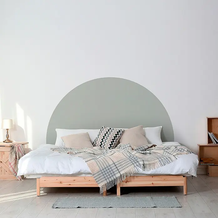 Vinilo de pared autoadhesivo Arco Verde Eucalipto - 132 x 170 cm, Verde, Plástico - Acogedora habitación con una cama cómoda adornada con almohadas y una manta suave, frente a un elegante diseño de pared.