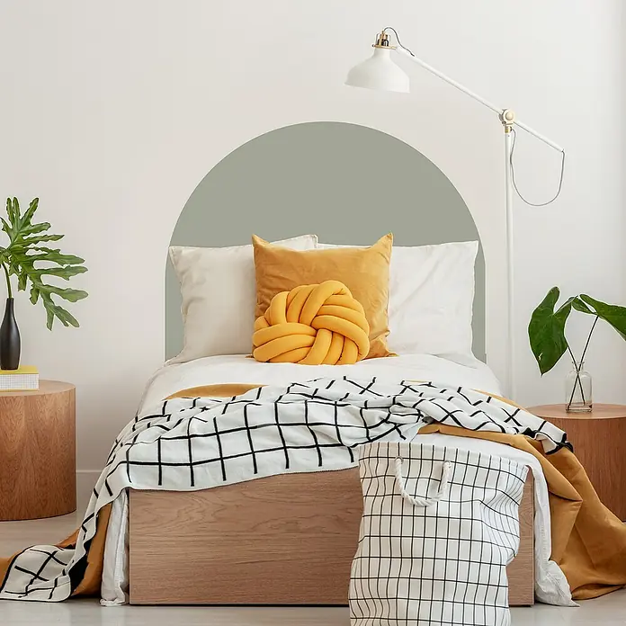 Vinilo de pared autoadhesivo Arco Verde Eucalipto - 110 x 132 cm, Verde, Plástico - Elegante dormitorio con cama, cojín amarillo y colcha a cuadros para un ambiente acogedor.
