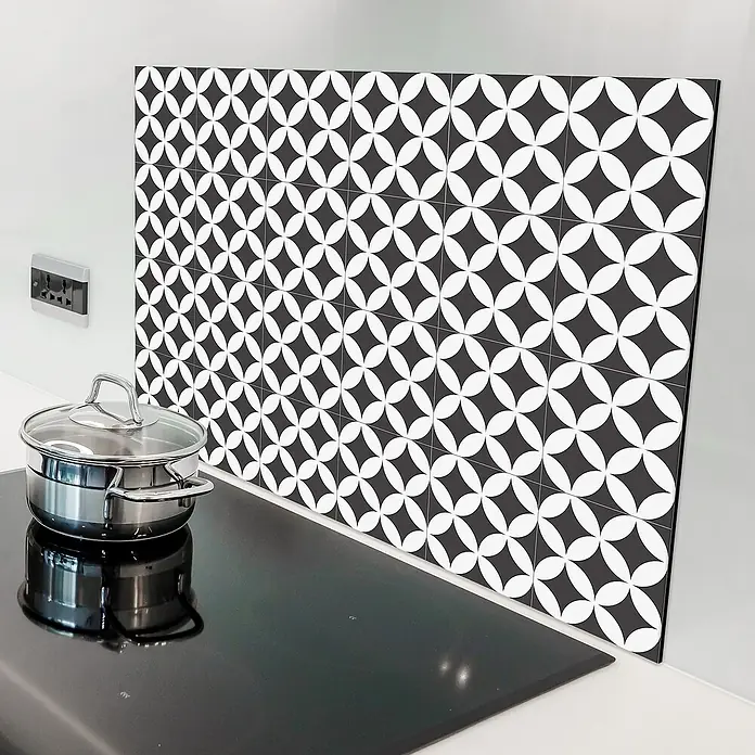 Panel de pared salpicadero de cocina Mosaic - L x An: 90 x 60 cm - Vista de la cocina con una placa negra, una olla y un protector contra salpicaduras con un diseño geométrico blanco y negro.