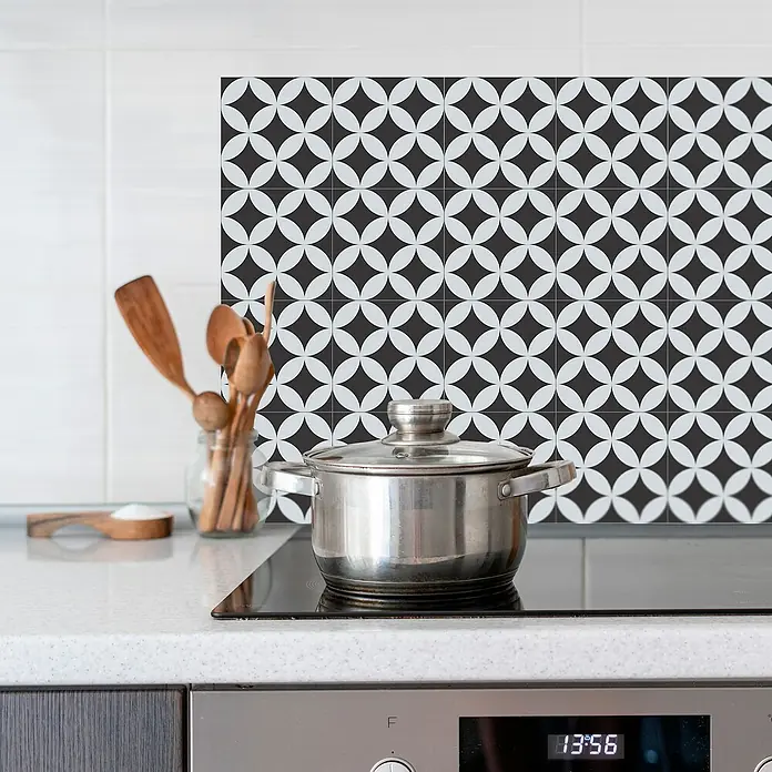 Panel de pared salpicadero de cocina Mosaic - L x An: 90 x 60 cm - Una olla de acero inoxidable con tapa está sobre una moderna placa de inducción frente a un elegante protector de cocina con diseño geométrico.