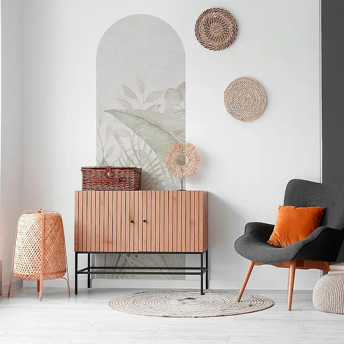 Vinilo de pared autoadhesivo Arco Tropic Calm - 65 x 200 cm, Gris, Plástico - Idea de diseño de interiores con un armario de madera con elementos decorativos, una silla de ratán y un sillón gris con un cojín naranja para un ambiente acogedor.