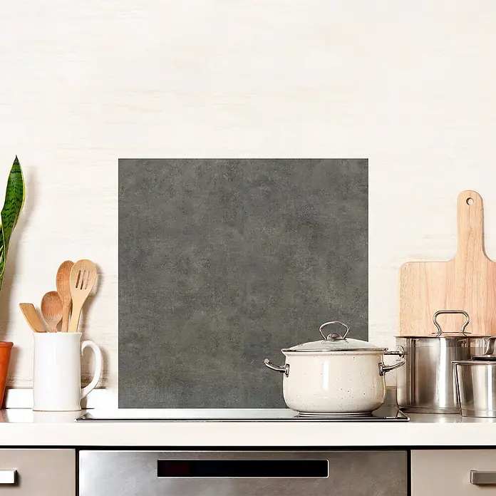 Panel de pared salpicadero de cocina Concret - L x An: 60 x 60 cm - Primer plano de una encimera de cocina con ollas, utensilios y un protector contra salpicaduras gris, creando un ambiente de cocina moderna.
