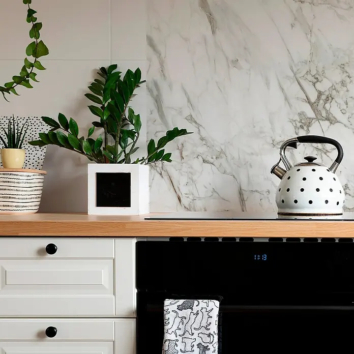 Panel de pared salpicadero de cocina Marble - L x An: 90 x 60 cm, Café - Primer plano de una cocina con una elegante tetera blanca de lunares sobre una placa de cocina, que irradia elegancia.