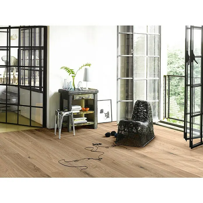 Parador Parkettmuster Classic 3060 Living Eiche II - 200 x 185 x 13 mm, Landhausdiele - Einladender Raum mit stilvollem Eichenparkettboden, einem Design-Sessel und dekorativen Elementen, die ein modernes Ambiente schaffen.