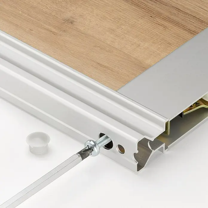 Room Plaza Easy Schiebetür-Bau-Set - Eiche Country/Pinie White, Farbe Beschlag: Silber - Detailansicht einer Aluminium-Übergangsschiene für Bodenbeläge, die mit einem Schraubenzieher montiert wird. Bodenzubehör für nahtlose Übergänge.