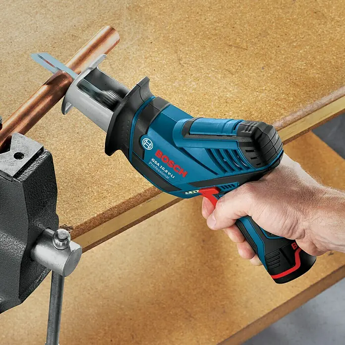 Bosch Professional Akku-Säbelsäge GSA 12V-14 - 12 V, Li-Ionen, Ohne Akku, Leerlaufhubzahl: 0 /min - 3.000 /min - Die Bosch GSA 10,8 V-LI Akku-Säbelsäge schneidet ein Kupferrohr in einem Schraubstock, demonstriert ihre kompakte Bauweise und Leistung.
