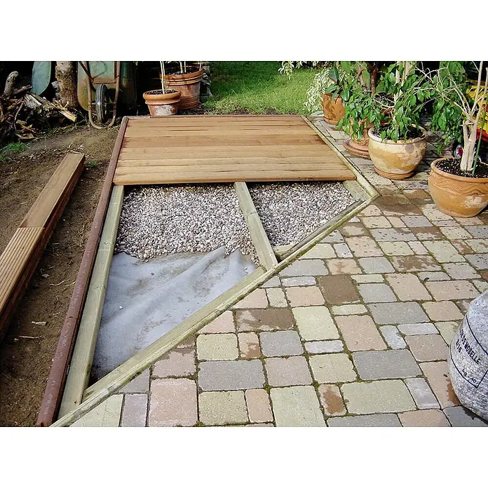 Gardol Premium Filtervlies - 20 x 1 m - Nahaufnahme einer sich im Bau befindlichen Holzterrasse mit Steinen und Pflastersteinen im Außenbereich.