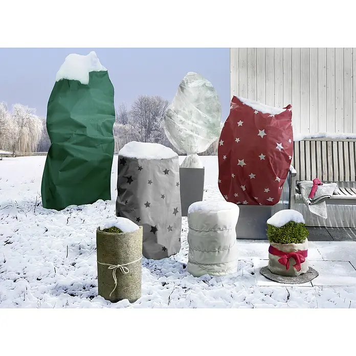 Floraworld Classic Jute-Gewebematte - Natur, 500 cm - Mehrere Pflanzen in verschiedenen Pflanzgefäßen sind mit Winterschutzhüllen in einer Schneelandschaft abgedeckt.
