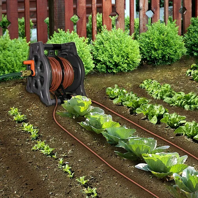 Elgo Tropfer-Set Drip`N Roll - Geeignet für: Flächen bis 60 m², Transportfähig - Bewässerungssystem für den Garten mit einem Schlauchaufroller und einem braunen Schlauch, der zu den Pflanzen führt.