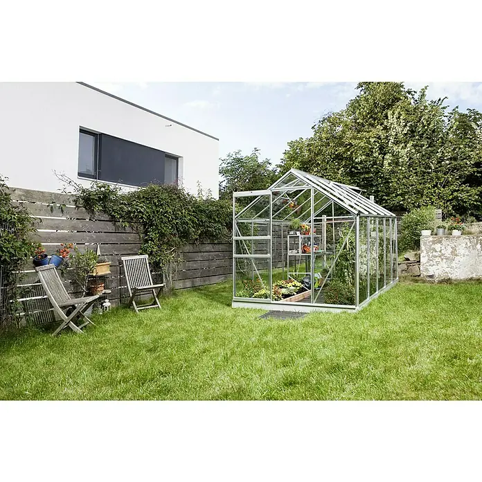 Vitavia Gewächshaus Venus 6200 Plus - Außenmaß inkl. Dachüberstand (B x T): 195 x 321 cm, 3 mm, Aluminium - Ein helles Gewächshaus aus Glas und Metall steht im Garten. Es beherbergt eine Vielzahl von Pflanzen und Blumen und bietet optimalen Wachstum.
