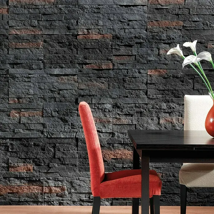 Revestimiento de piedra Salonica Onix - 60 x 30 x 2 cm - Paneles de pared negros con diseño de piedra detrás de una mesa de comedor con una silla roja y flores en un jarrón.