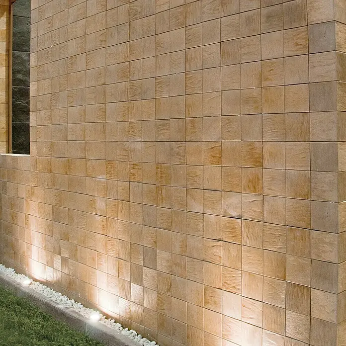 Revestimiento de piedra Teka - Cantidad total: 4 pzs. - Primer plano de una pared con piedra chapa cuadrada en tonos tierra cálidos e iluminación suave que acentúa la textura.