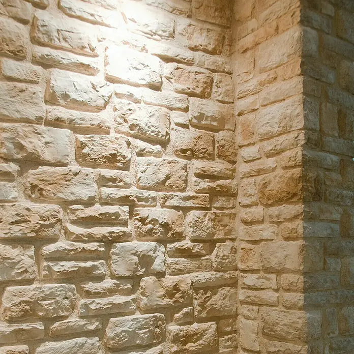 Esquina exterior Silleria Cobre - Cantidad total: 9 pzs. - Primer plano de una pared de piedra rústica, que muestra una superficie cálida, texturizada y detalles arquitectónicos.