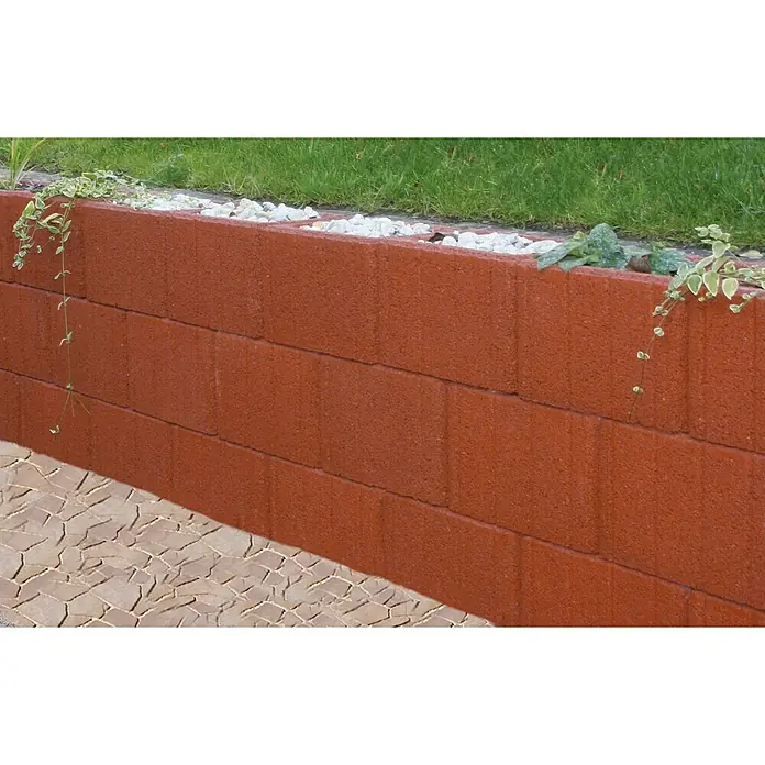 Christoph Pflanzstein MultisteinToskana, 45 x 30 x 30 cm, Beton - Diese Aufnahme zeigt eine dekorative rote Steinmauer, die einen erhöhten Garten mit Grünflächen und weißen Steinen abgrenzt.