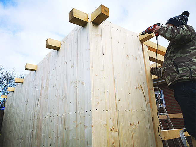 Person mit Bohrmaschine beim Gartenhaus günstig selber bauen