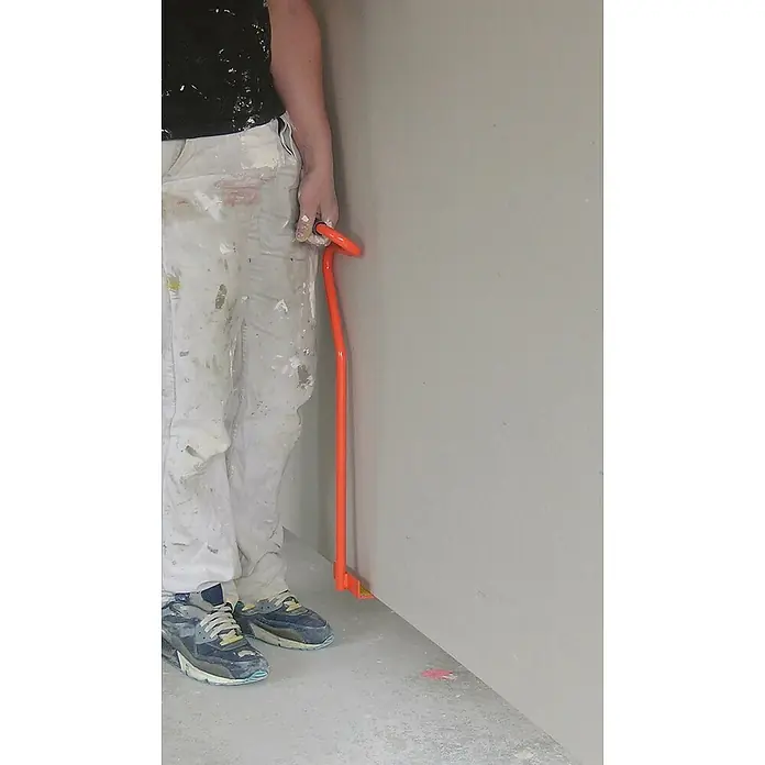 Mondelin Tragegriff - Gesamtlänge: 62 cm, Geeignet für: Gipskartonplatten - Ein Arbeiter mit einer orangefarbenen Sockelleistenhebel. Ideal zum schonenden Entfernen von Fußleisten und spart Zeit und Mühe.