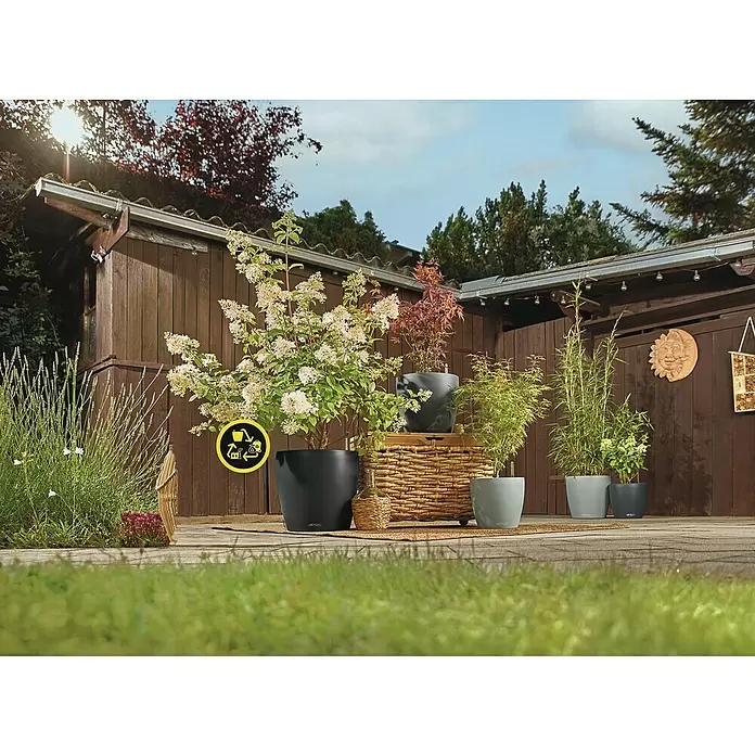 Lechuza Classico Pflanztopf Eco - Außenmaß (Ø x H): 34,5 x 32,5 cm, Kunststoff, Hellgrau - Sortiment aus dunkel- und hellgrauen Pflanzgefäßen mit Pflanzen auf einer Terrasse, ein Recycling-Logo ist auf einem Topf sichtbar.
