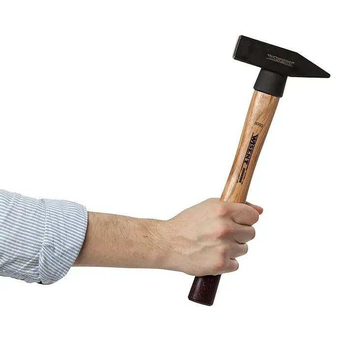 Wisent Martillo de cerrajero - 800 g, Acero, Mango de madera nogal - Un hombre sostiene un martillo de cerrajero WISENT con mango de madera. La herramienta está diseñada para trabajos precisos.