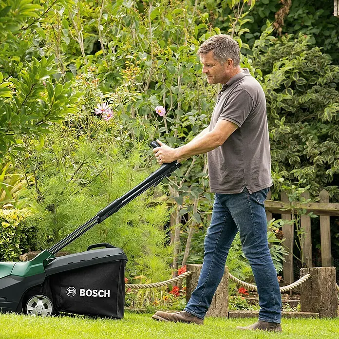Bosch Power for All 36V Akku-Rasenmäher AdvancedRotak 36V-44-750 - 36 V, Ohne Akku, 0 Ah, Schnittbreite: 44 cm - Ein Mann mäht den Rasen mit einem Bosch Rasenmäher. Der Rasenmäher hat einen Grasfangkorb und ist in Grün und Schwarz gehalten.