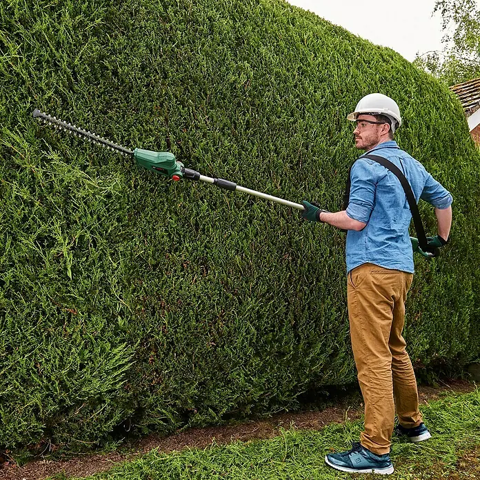 Bosch Power for All 18V Teleskop-Heckenschere UniversalHedgePole 18 - 18 V, Li-Ionen, Ohne Akku, Schnittlänge: 43 cm - Ein Mann mit einer Akku-Heckenschere beim Schneiden einer Hecke. Die Heckenschere ist ideal für hohe Hecken.
