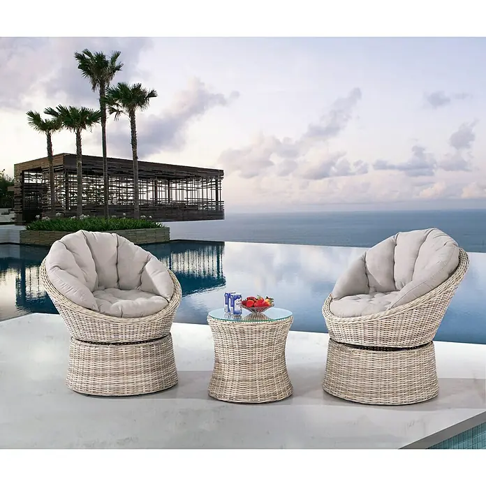 Sunfun Cojín de asiento Conjunto Milano - Poliéster, Arena - Dos sillas de mimbre y una mesa auxiliar de mimbre con bebidas y fruta en un patio con vistas al océano.