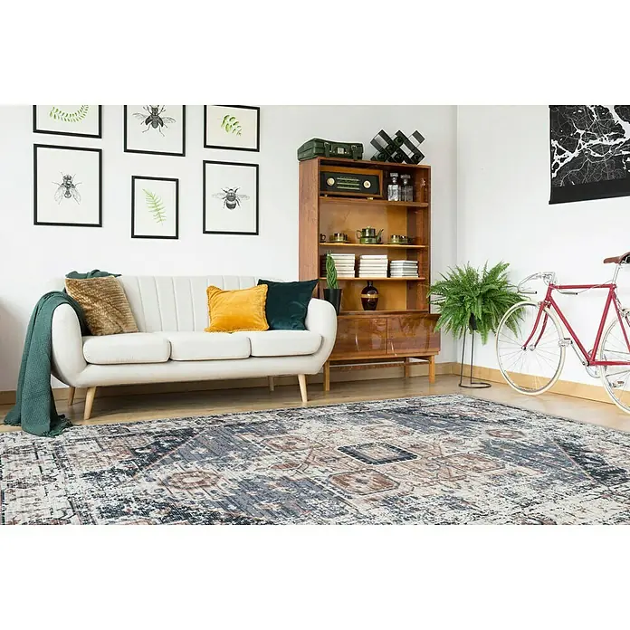 Kayoom Kurzflorteppich Indiana - Grau/Braun, 150 x 80 cm, 100 % Baumwolle - Ein stilvoller Wohnraum mit einem dekorativen Teppich, der dem Raum Wärme und Eleganz verleiht. Das Möbelstück ist in Beige gehalten.