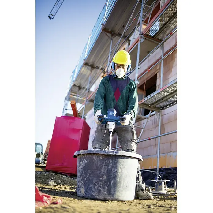 Scheppach Varilla mezcladora de pintura y mortero PM1200 - 1.200 W, Diámetro paleta de mezcla: 120 mm, M 14 - Un constructor mezcla material con una mezcladora Scheppach en una obra rodeada de andamios y materiales.