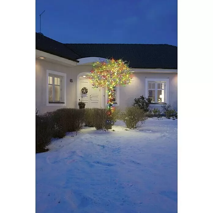 Konstsmide LED-Lichterkette Micro - Außen, Lichtfarbe: Mehrfarbig, Anzahl Leuchtmittel: 120 Stk., Netzbetrieben - Bunte LED-Lichterketten beleuchten einen Baum im verschneiten Garten in der Dämmerung.