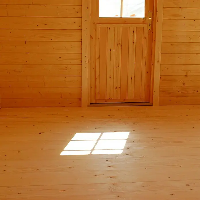 Palmako Bodenplatte Marseille 1 - Fichte - Hölzerner Innenraum mit Holztür und Fenster, die Licht auf den Holzboden werfen, wodurch die natürliche Holzmaserung betont wird.