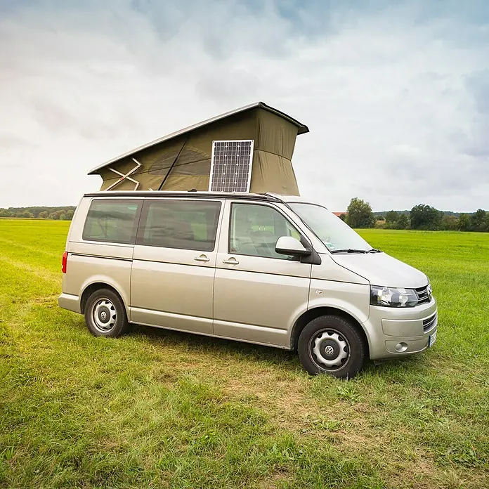 Sunset Solarmodul-Set Laminat - Nennleistung: 70 W, Für Booten, Yachten und Wohnmobilen - Seitenansicht eines silbernen VW-Campingbusses mit Solarpaneel auf dem Dach und hochgeklapptem Zeltaufbau auf einer grünen Wiese.