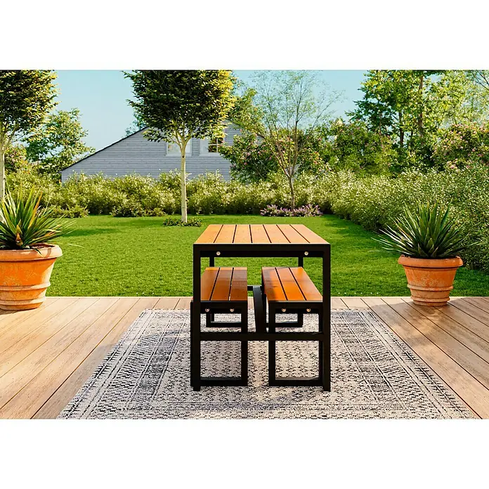 Promadino Gartenmöbel-Set Sylt - 3 -tlg., Kiefernholz, Braun/Schwarz - Ein moderner Gartentisch mit integrierten Bänken auf einem stilvollen Outdoor-Teppich, umgeben von üppigem Grün und Pflanzen in Töpfen.