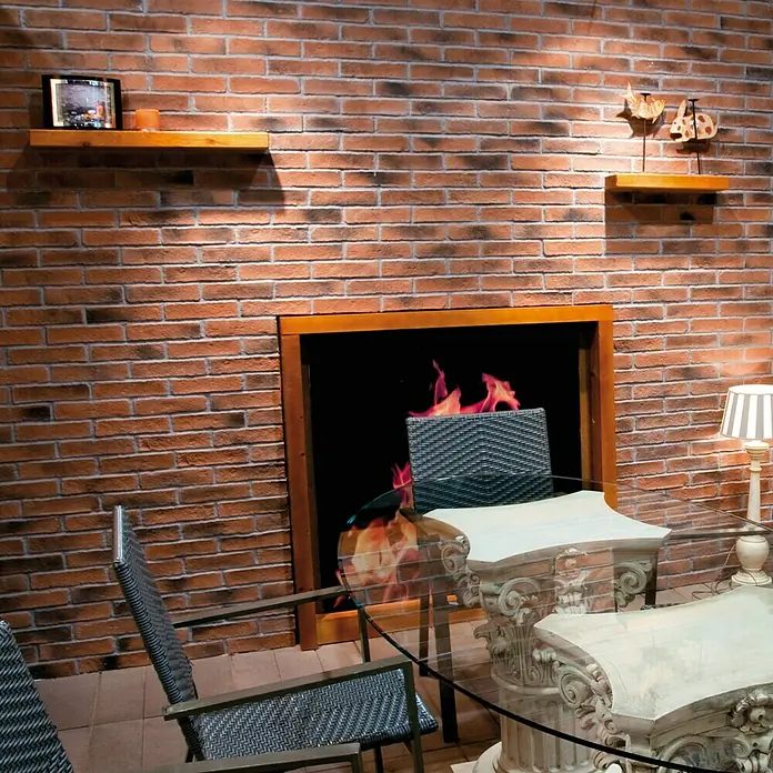Revestimiento de piedra Mediterráneo Teja - 24 x 5,5 x 2,5 cm - Interior acogedor con una mesa y sillas elegantes frente a una chimenea simulada, creando un ambiente cálido y confortable.