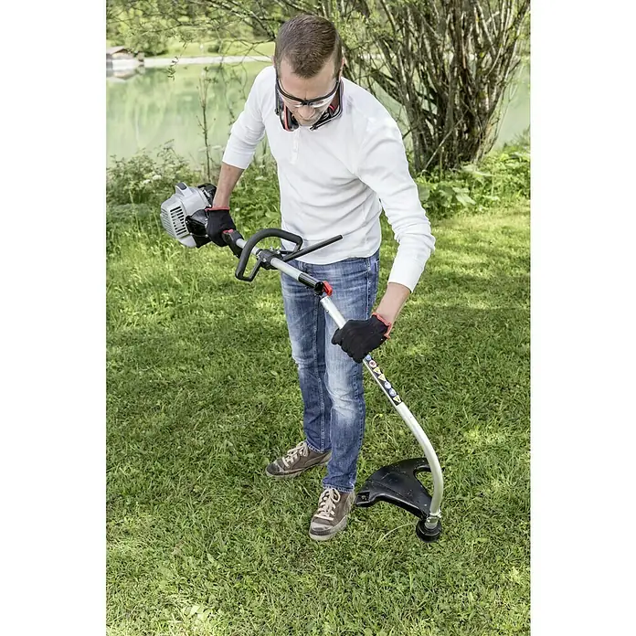 AL-KO Benzin-Motorsense BC 223 L-S - 700 W, Schnittbreite Faden: 41 cm - Mann bedient einen Rasentrimmer im Freien mit Schutzbrille und Handschuhen, um den Garten zu pflegen. Ideal für präzise Rasenpflege.