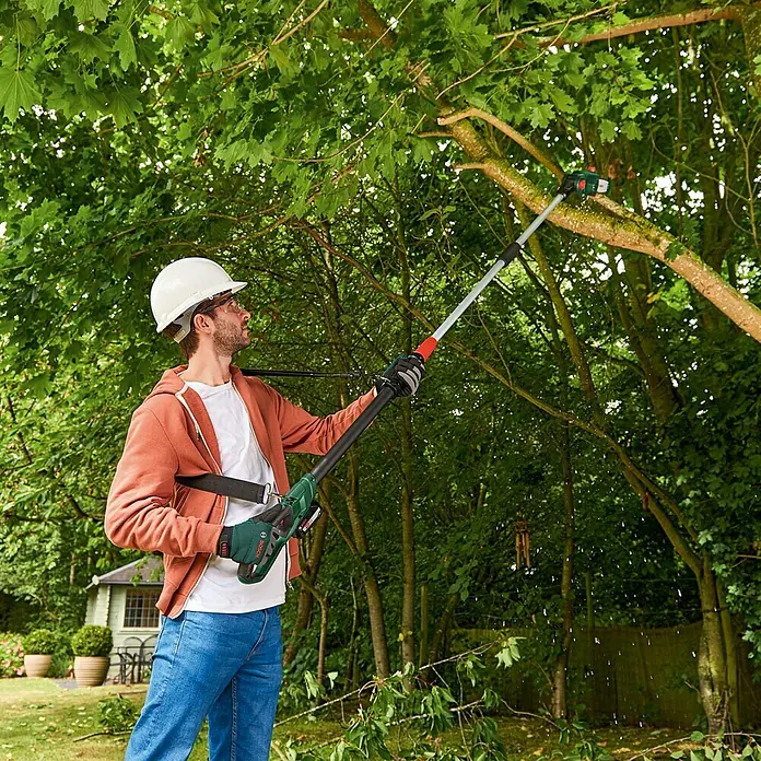 Bosch Power for All 18V Akku-Hochentaster UniversalChainPole 18 - 18 V, Li-Ionen, Ohne Akku - Ein Mann mit einem Bosch Hochentaster beim Baumschnitt, ausgestattet mit Helm und Handschuhen, für sichere Gartenarbeit.