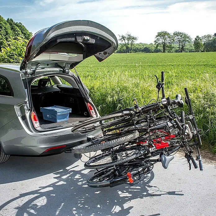 Eufab Fahrradträger Amber IV - Geeignet für: 4 Fahrräder, Passend für: Fahrzeuge mit Anhängerkupplung - Fahrradträger am Heck eines Autos mit geöffneter Heckklappe. Ein blauer Kasten befindet sich im Kofferraum.