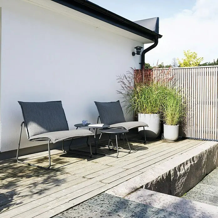 Sunfun Sarah Garten-Beistelltisch rund - Ø x H: 60 x 41,5 cm, Stahl, Schwarz - Zwei graue Sessel und ein Tisch auf einer Terrasse. Die Gartenmöbel laden zum Entspannen im Freien ein.